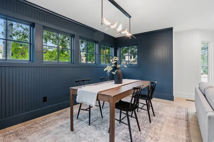 Board and batten wall paneling, light wood-finish flooring, white trim, and a linear chandelier