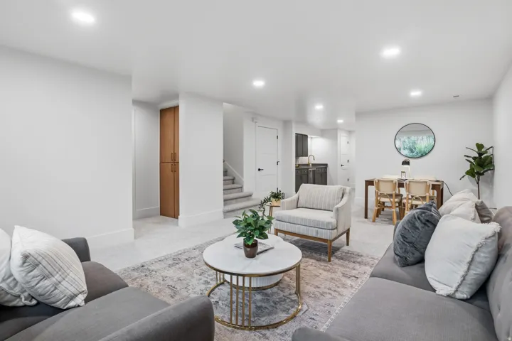 Recessed lighting illuminates the open living space, featuring light-toned walls and a built-in wood-finish cabinet