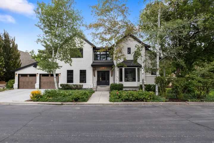 White shingle-style exterior with dark trim accents, featuring a prominent bay window
