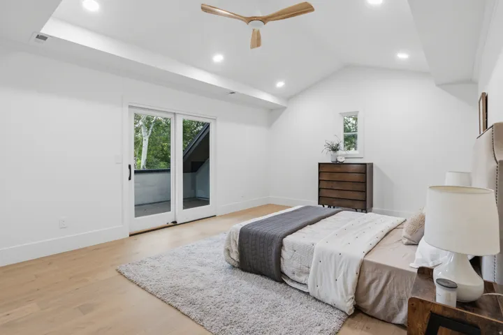 Vaulted ceiling with recessed lighting, wood-finish flooring, sliding glass door to exterior, and a wood-bladed ceiling fan