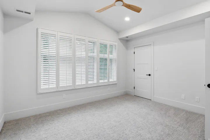 Vaulted ceiling, recessed lighting, wood-finish ceiling fan, plantation shutters, and light-tone carpet