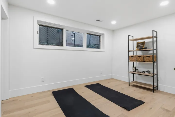 Recessed lighting, wood-finish flooring, white walls, and a three-pane window