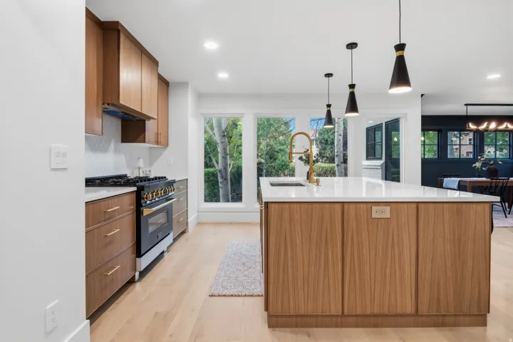 Modern kitchen featuring wood-finish cabinetry, white countertops, and a white tile backsplash