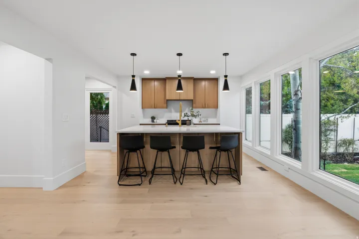 Open-concept kitchen with light wood-finish flooring, a large island with countertop, and two-tone cabinetry