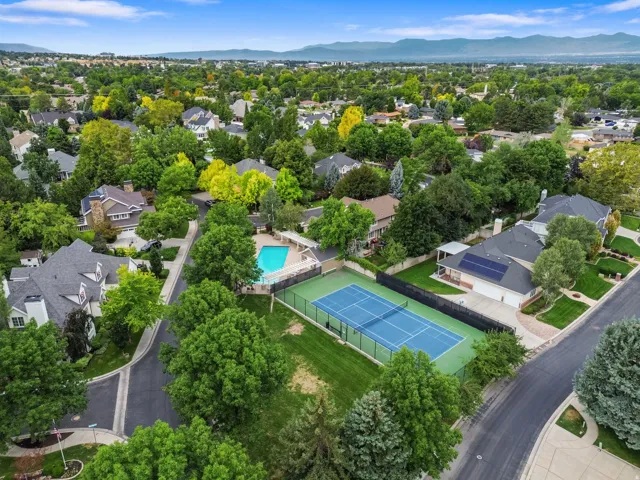 Neighborhood featuring mature trees, residential properties, a tennis court, a swimming pool, and distant mountains