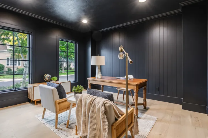 Black interior walls, light wood-finish flooring, recessed lighting, crown molding, and two multi-pane windows