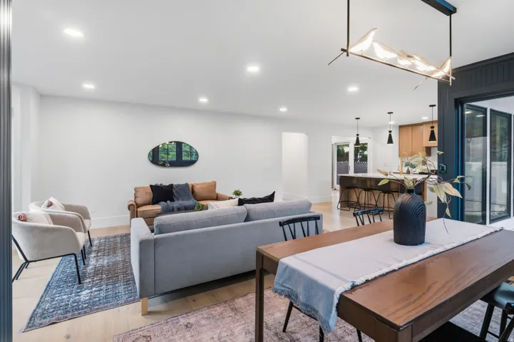 Open-concept living area with recessed lighting, wood-finish flooring, and a contemporary linear chandelier