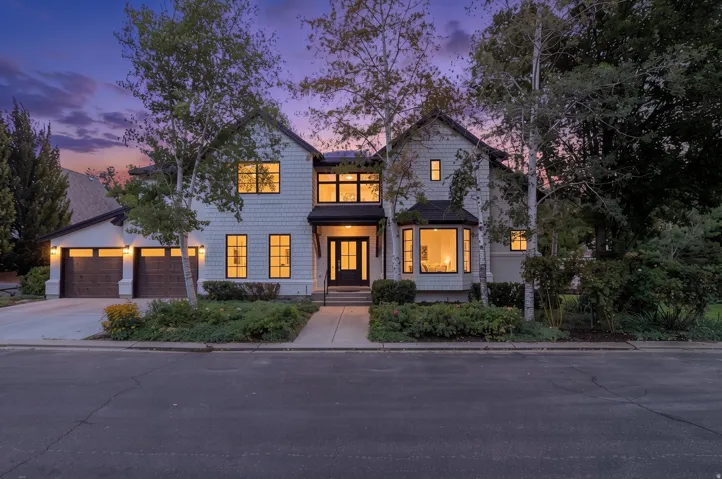 Two-story residence featuring light-colored siding, dark-trimmed windows, and a two-car garage with wood-finish doors