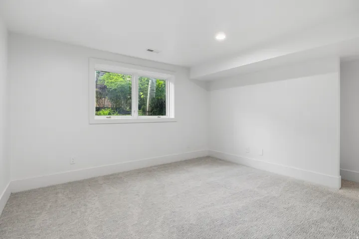 Recessed ceiling lighting, a framed window, light gray carpet, white walls, and white trim
