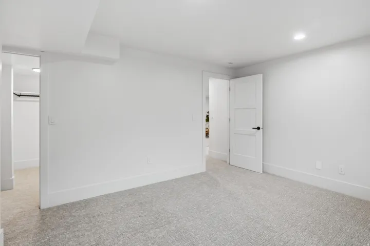 Neutral-toned carpeting, recessed lighting, and a white interior door with black hardware