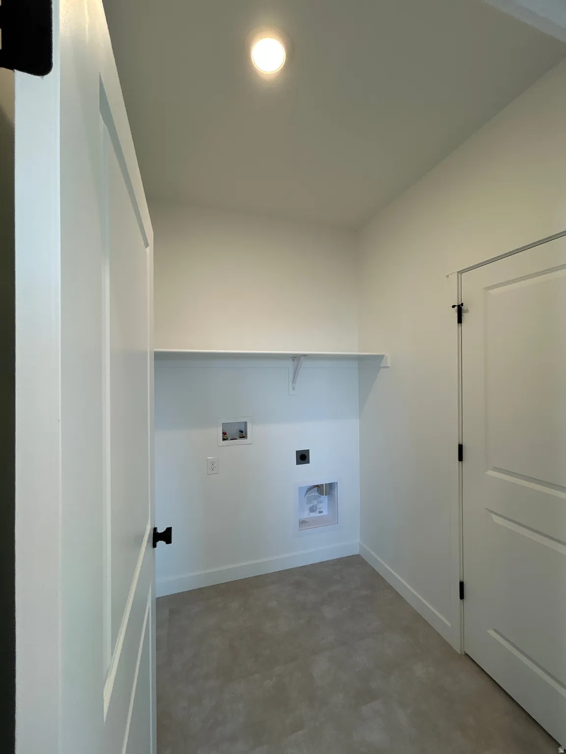 Laundry area with a built-in shelf, neutral wall color, and light-toned flooring