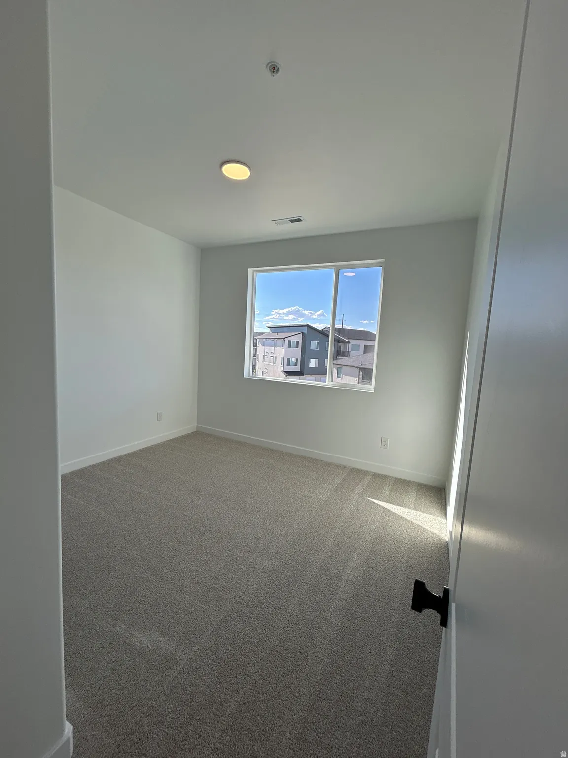 Wall-to-wall carpeting, recessed lighting, and a window with white trim