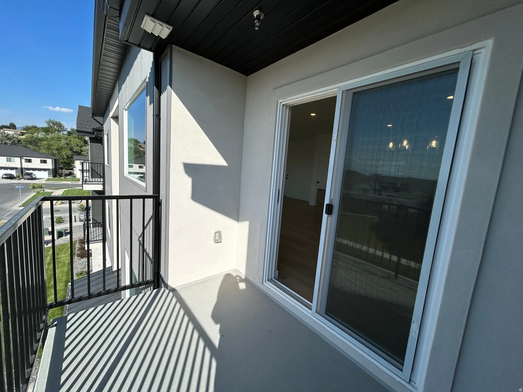Balcony with black metal railing, sliding glass door, and light gray exterior stucco