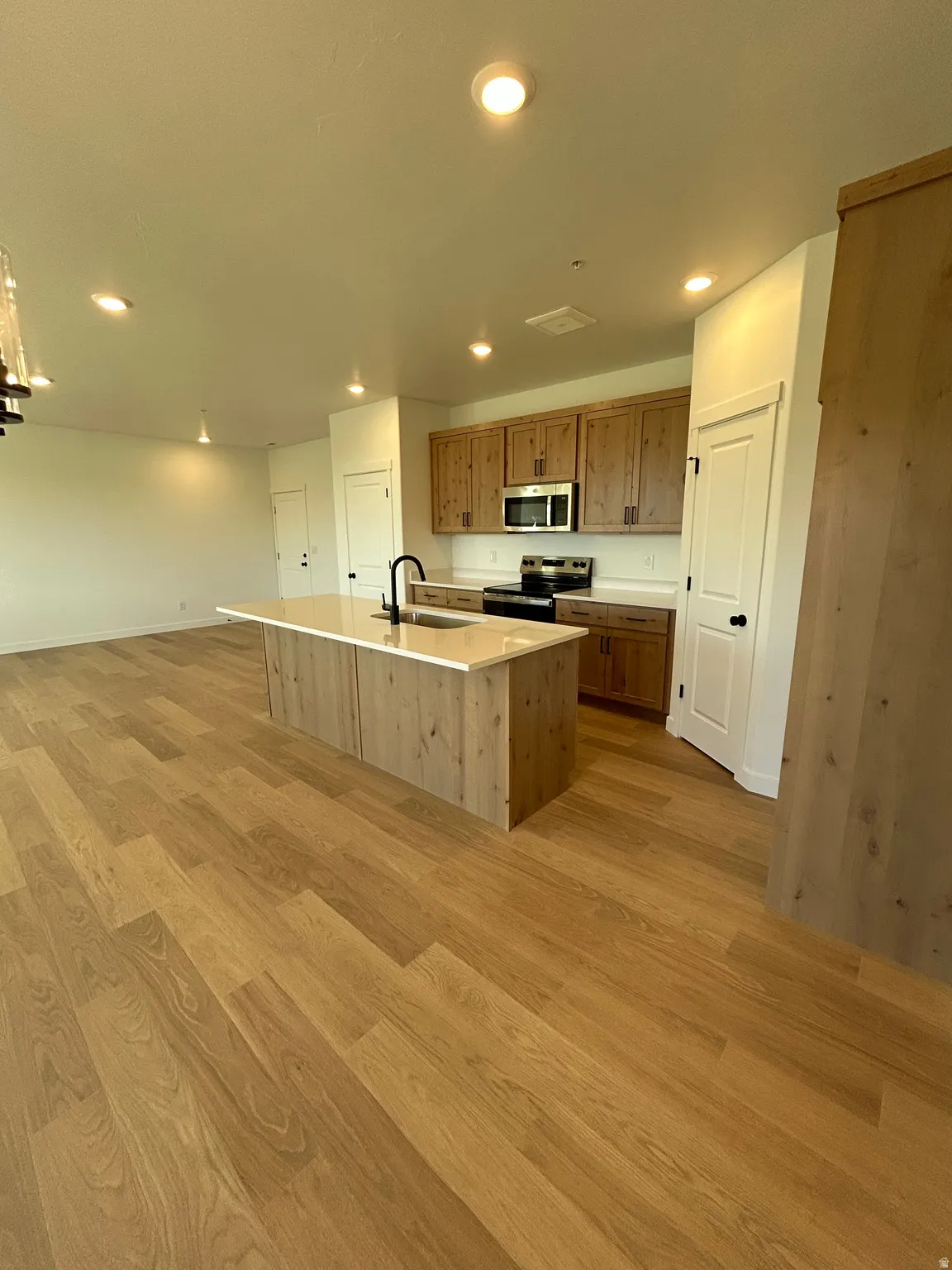 Open-concept kitchen with a central island, wood-finish flooring, recessed lighting, and wood cabinetry