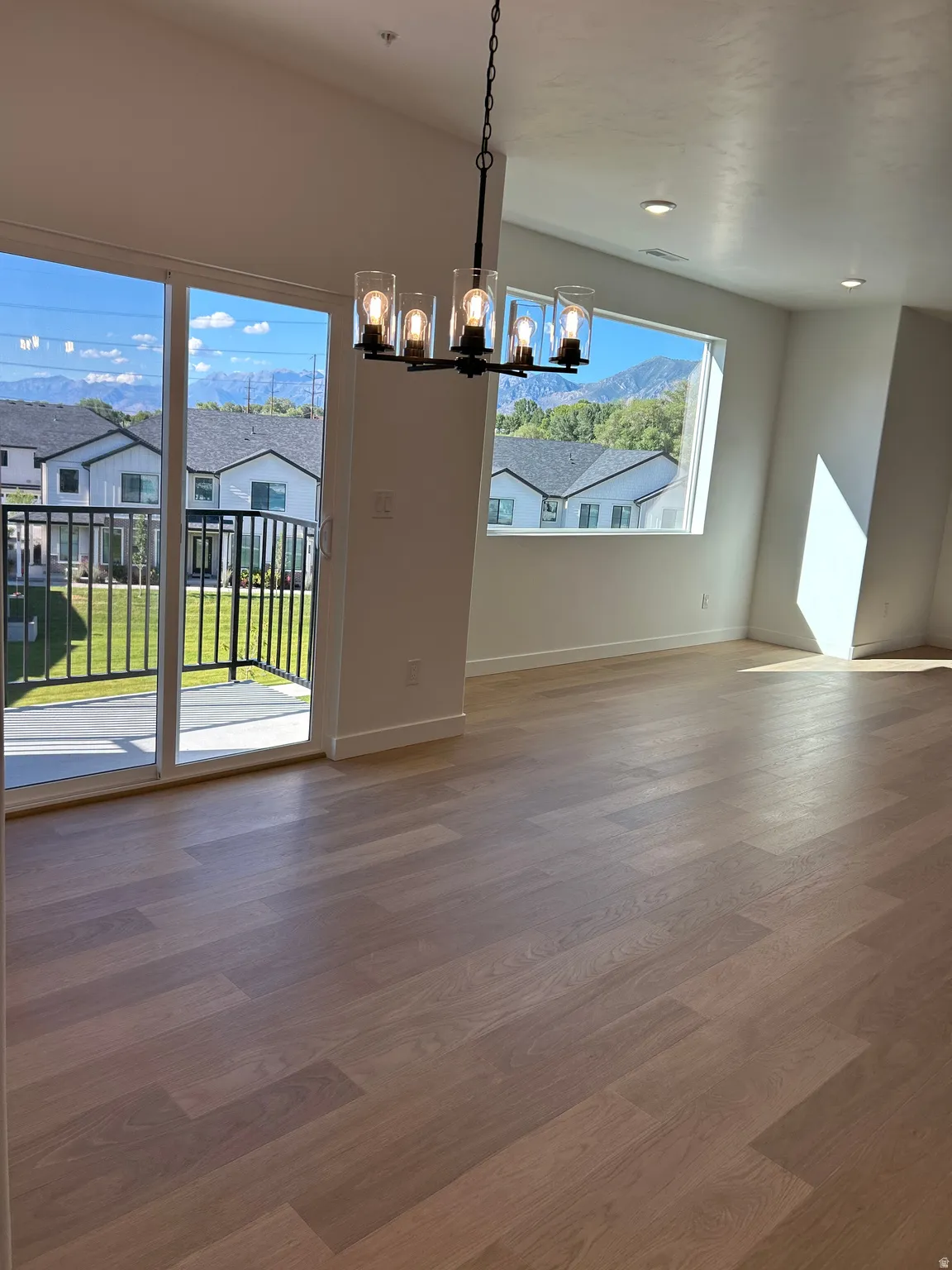 Wood-finish flooring, a contemporary chandelier, recessed lighting, and sliding glass door with balcony access