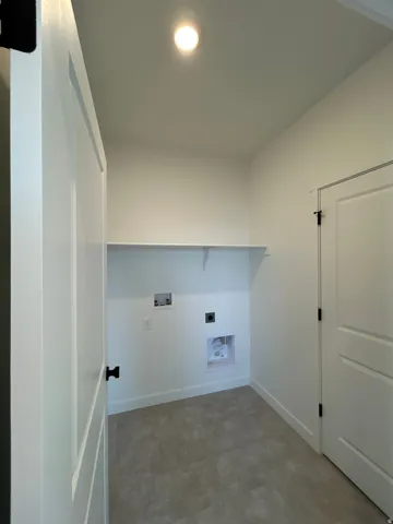 Laundry area with a built-in shelf, neutral wall color, and light-toned flooring
