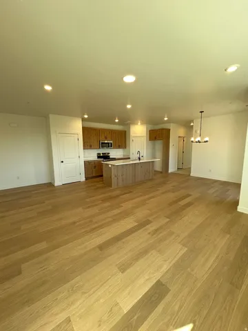 Open-concept kitchen and living area featuring wood-finish flooring, recessed lighting, and a kitchen island with a built-in sink