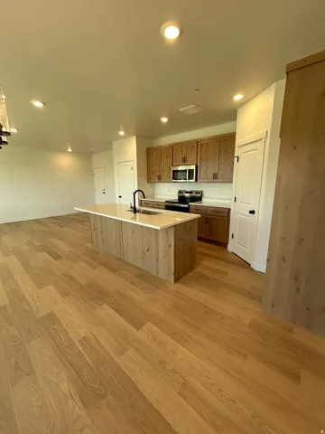 Open-concept kitchen with a central island, wood-finish flooring, recessed lighting, and wood cabinetry
