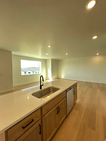Kitchen island with a built-in stainless steel sink, matte black faucet, and light-toned wood cabinetry