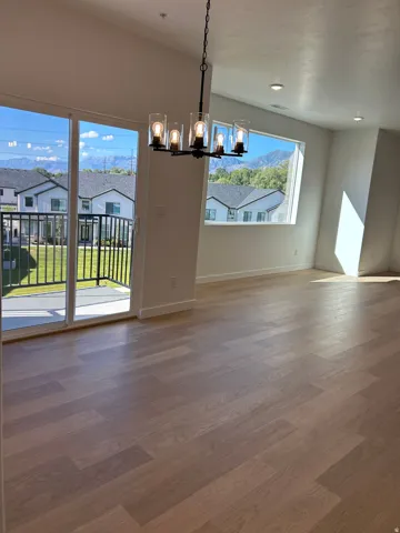 Wood-finish flooring, a contemporary chandelier, recessed lighting, and sliding glass door with balcony access