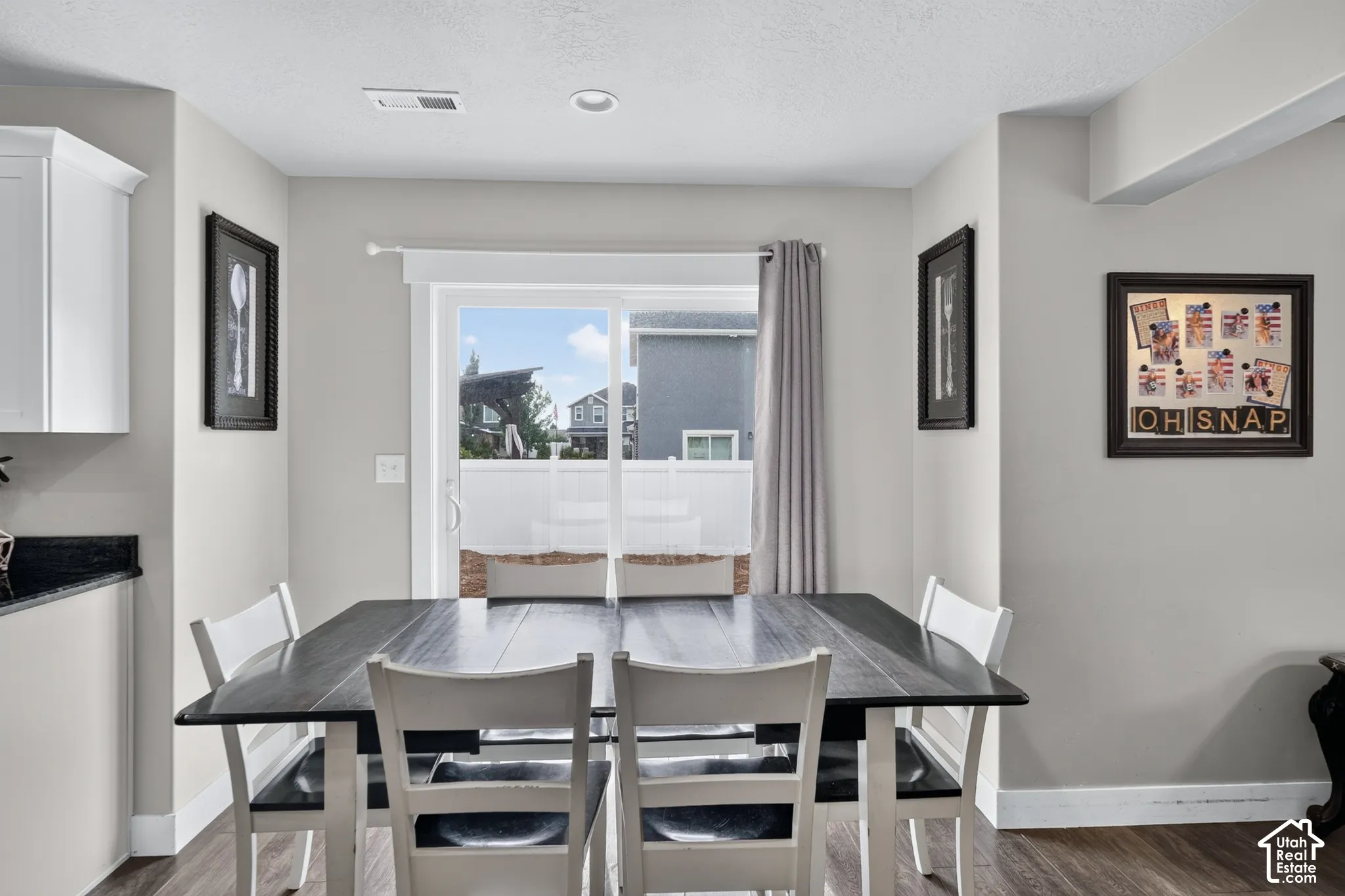 Sliding glass door to exterior, recessed lighting, wood-finish flooring, white cabinetry, dark countertop