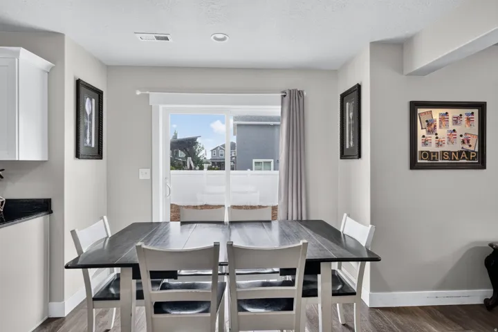 Sliding glass door to exterior, recessed lighting, wood-finish flooring, white cabinetry, dark countertop