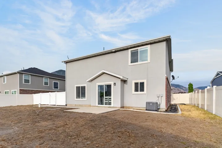 Stucco exterior with brick detailing, white vinyl fencing, and a concrete patio