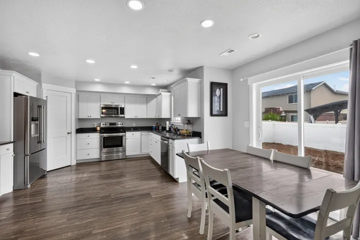 Modern kitchen featuring white cabinetry, dark countertops, stainless steel appliances, and wood-finish flooring