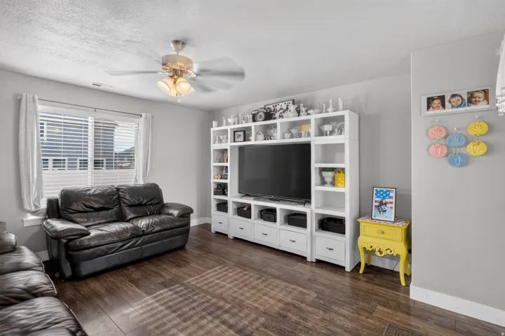 Wood-finish flooring, light grey wall paint, and a ceiling fan with integrated lighting