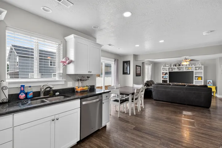 Kitchen featuring white cabinetry, dark stone countertops, and a stainless steel dishwasher