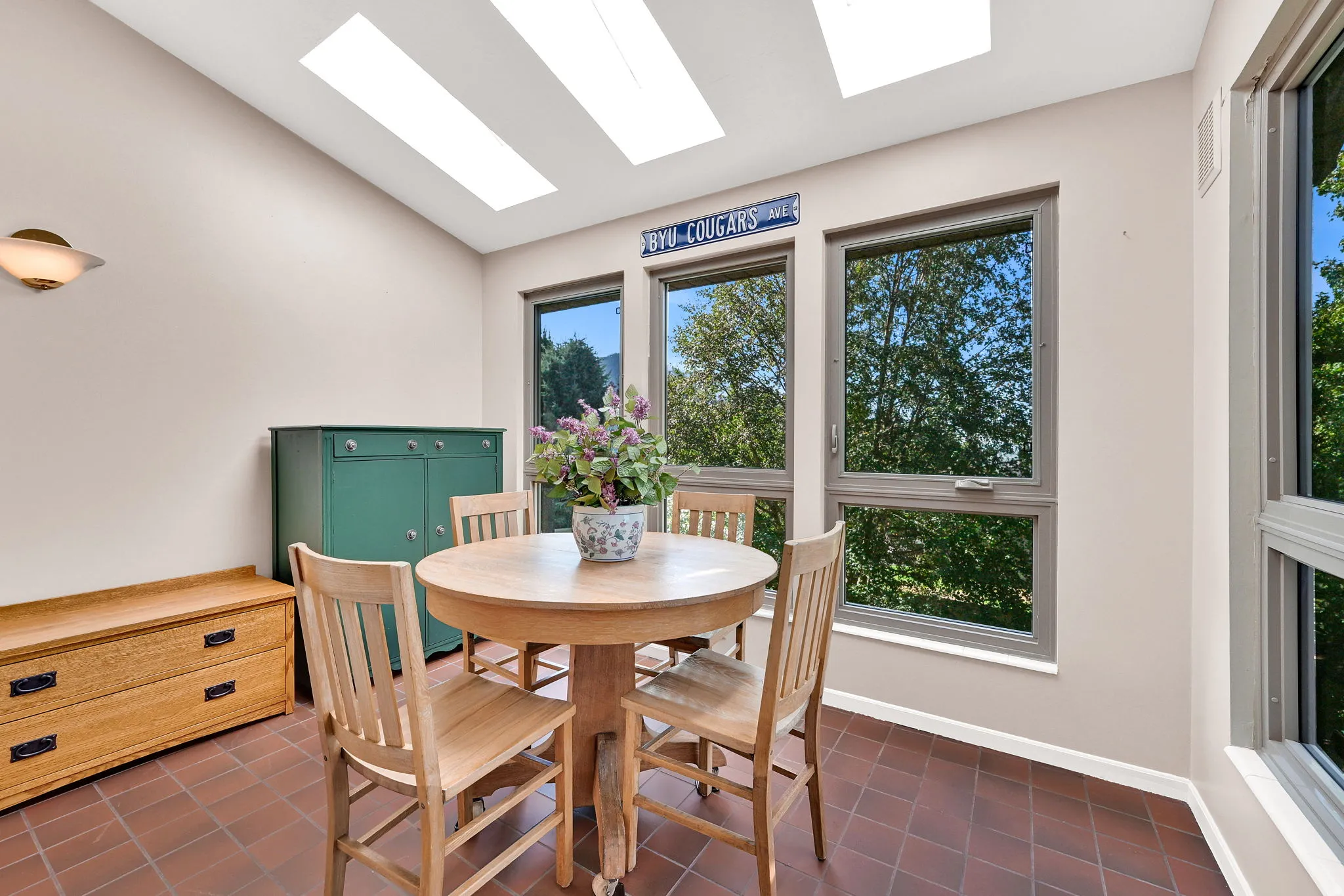Tile flooring, vaulted ceiling, multiple skylights, wall-mounted light fixture, expansive windows.