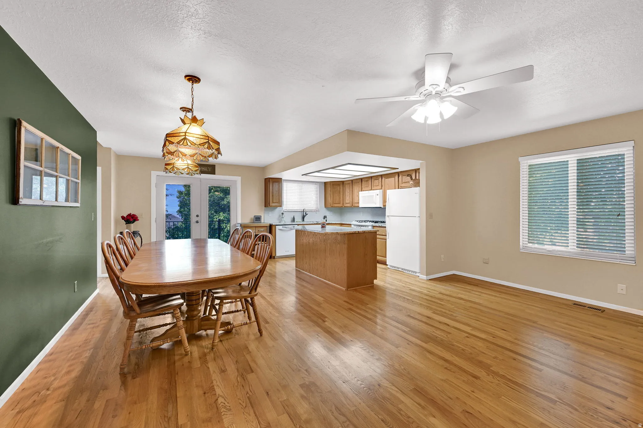 Hardwood flooring throughout, kitchen with wood cabinetry, white appliances, and a central island.
