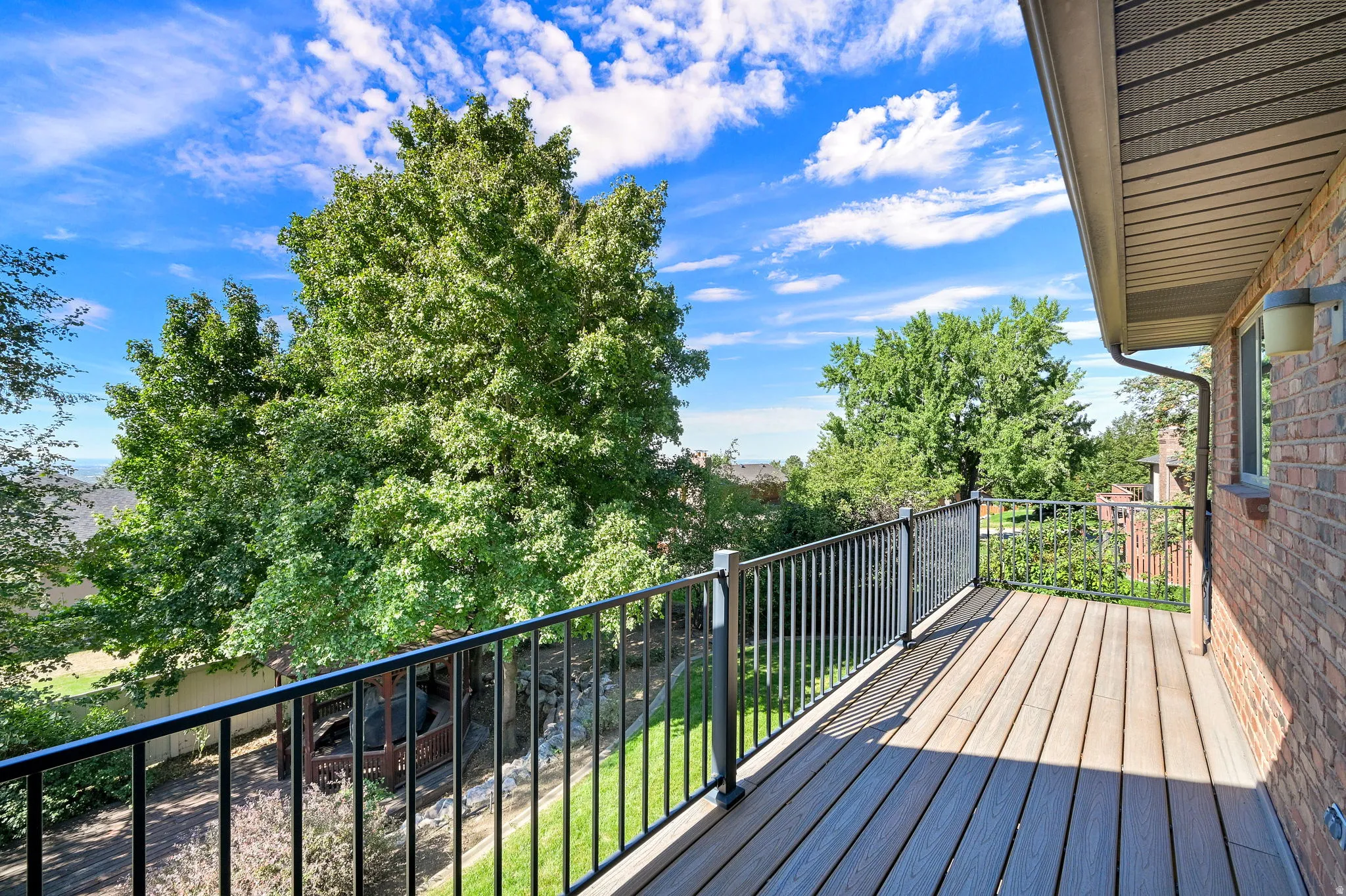 Elevated Trex deck with modern black metal railings overlooking mature landscaping in the backyard.