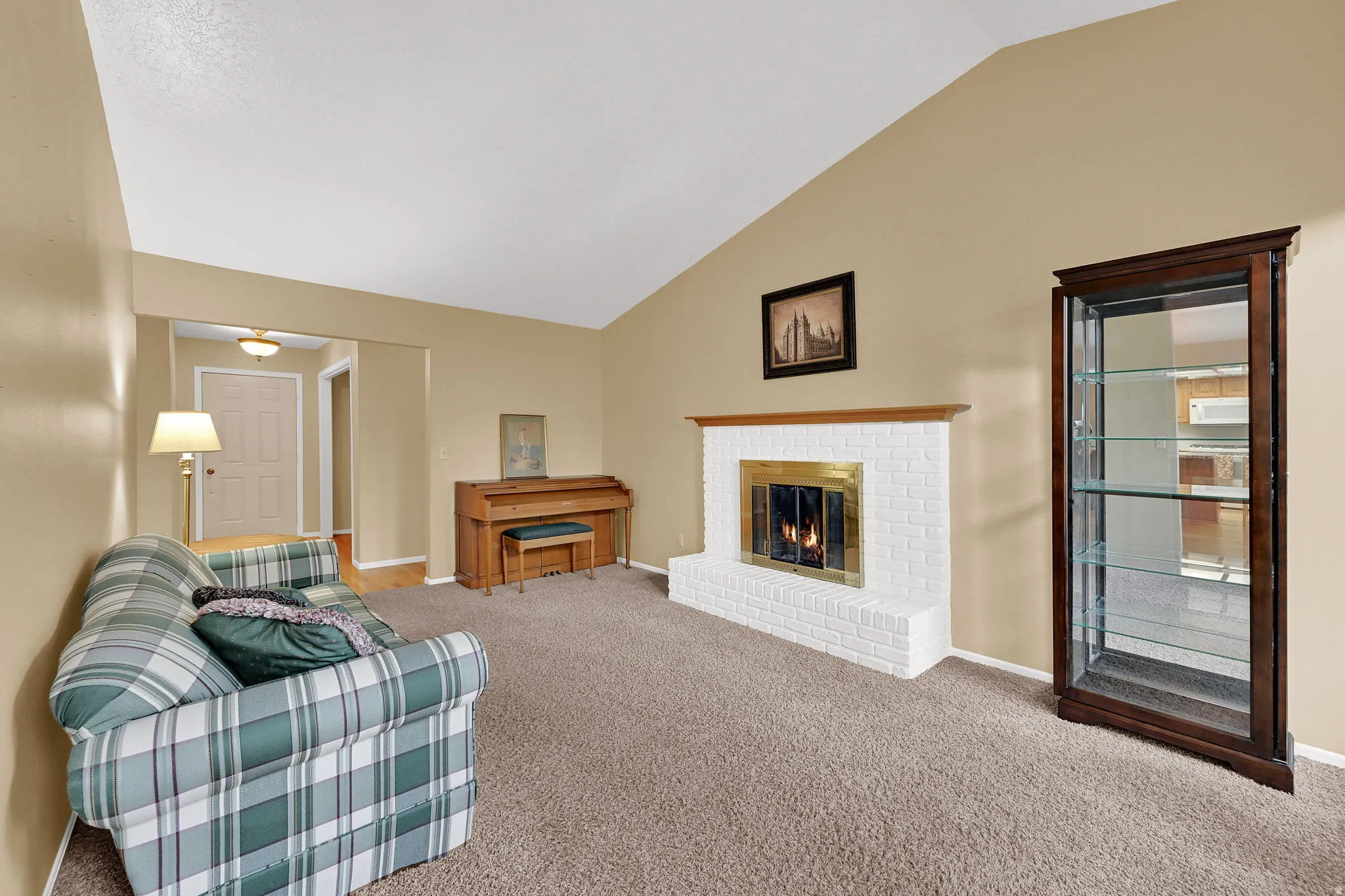 Vaulted ceiling, white brick fireplace with brass insert and wood mantel.