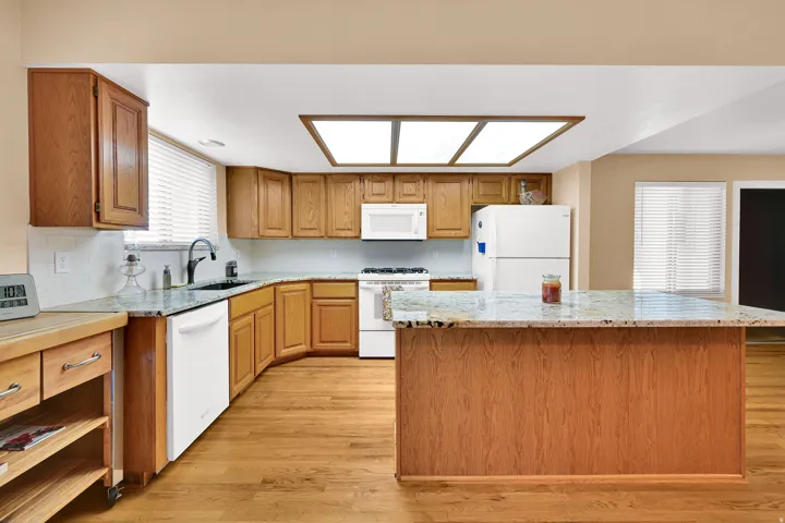 Hardwood flooring throughout the kitchen and an island with granite countertops.