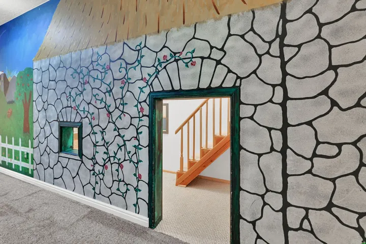 Decorative wall mural with stone-pattern design and painted vine accents for the exterior of the kids playroom.