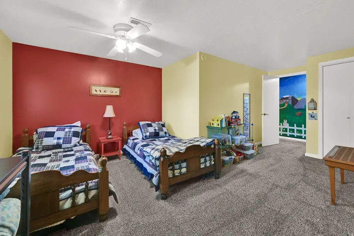 Large bedroom with wall-to-wall carpeting and a ceiling fan with integrated lighting