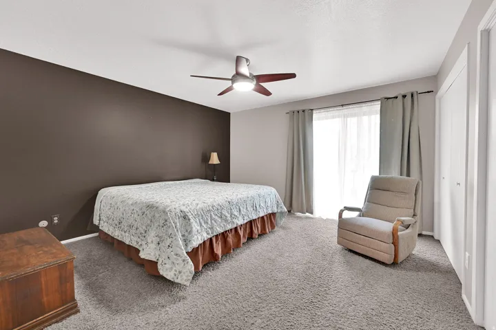 Wall-to-wall carpeting, ceiling fan with integrated lighting, sliding glass door to a private deck, and double-door closet.