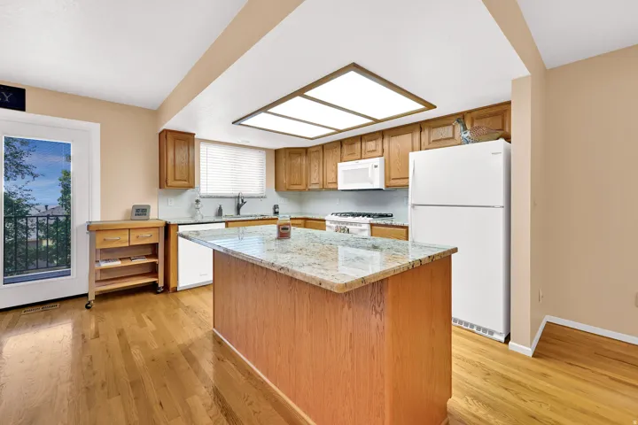 Kitchen featuring wood cabinetry, granite countertops, and white appliances.