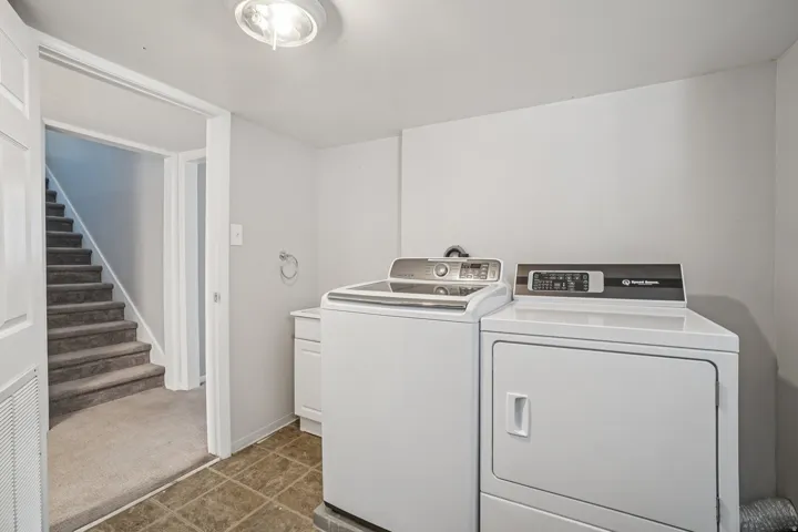 Dedicated laundry area with durable flooring, recessed lighting, and a white storage cabinet