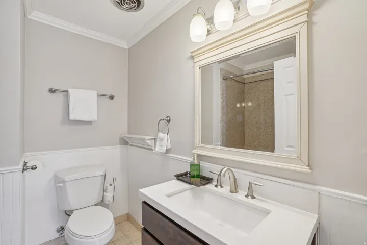 White beadboard wainscoting, a dark wood-finish vanity, and a white countertop with an integrated sink