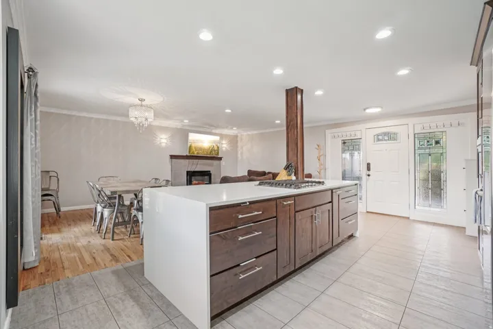 Kitchen island with integrated cooktop, quartz countertop, and dark wood-finish cabinetry