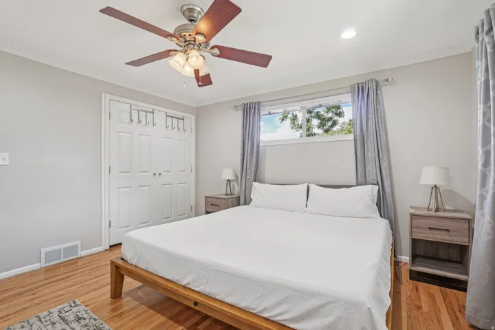 Hardwood flooring, overhead ceiling fan with lighting, double-door closet, and window with curtains
