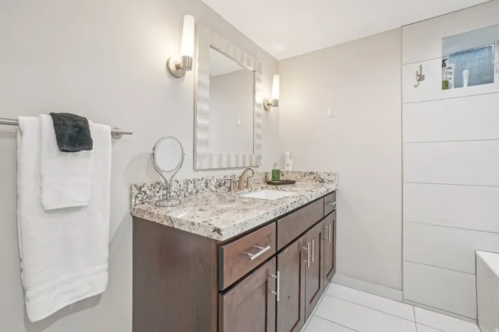 Extended vanity with stone countertop, undermount sink, and dark wood-finish cabinetry