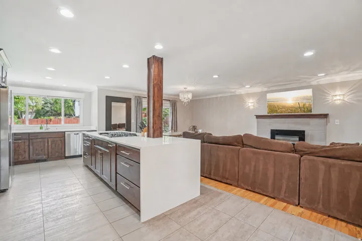 Kitchen and living area featuring a central island with a gas cooktop, recessed lighting, and a fireplace with a mantel