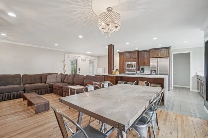 Open-concept living area with wood-finish flooring, recessed lighting, and a decorative chandelier