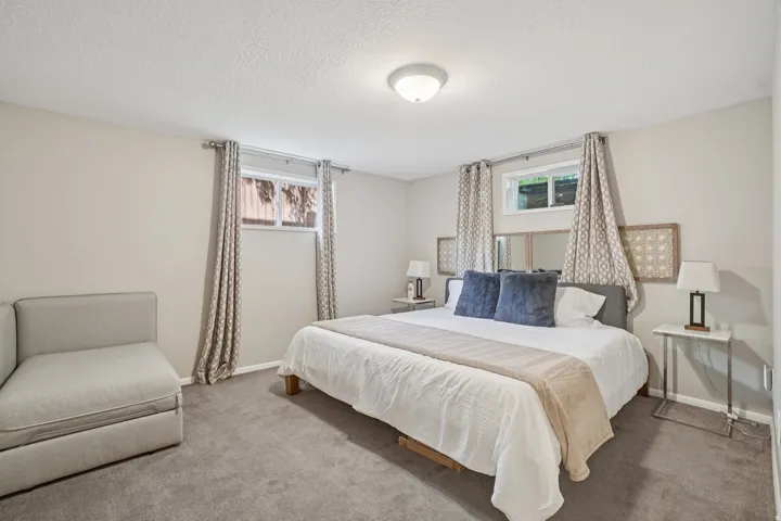 Neutral wall paint, ceiling-mounted light fixture, and two windows with light-filtering curtains