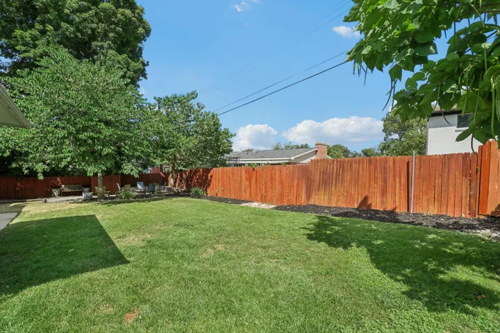 Expansive grassy yard with a wood privacy fence and mature trees