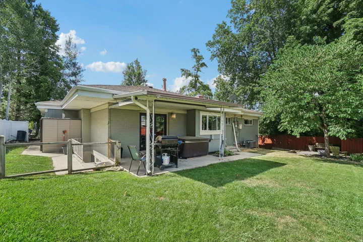Expansive backyard featuring a concrete patio, mature trees, and a privacy fence
