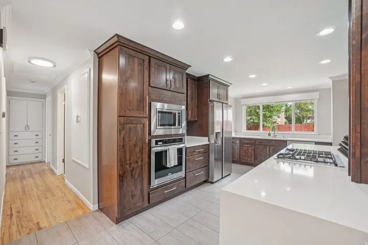 Kitchen featuring dark wood cabinetry, stainless steel appliances, a gas cooktop, white countertops, and recessed lighting